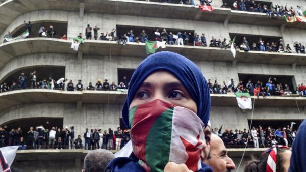 A woman covers her face with the national flag, as Algerian protesters demonstrate in the capital Algiers against ailing president's bid for a fifth term on March 8, 2019. 
RYAD KRAMDI / AFP