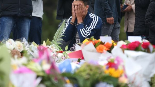 People pay their respects in front of floral tributes for victims of the March 15 mosque attacks, in Christchurch (AFP)