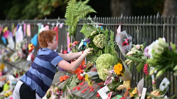 A child leaves flowers in tribute to victims in Christchurch (AFP)