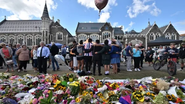 A group of students (C) sings in front of flowers left in tribute to victims at the Botanical Garden in Christchurch (AFP)