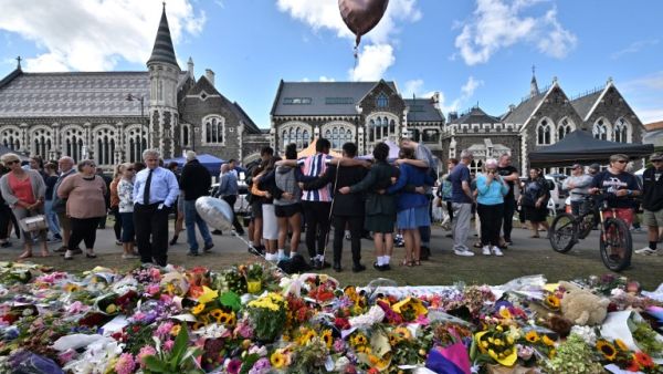 A group of students (C) sings in front of flowers left in tribute to victims at the Botanical Garden in Christchurch (AFP)