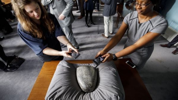 Members of the press take pictures of a Babylonian cuneiform kudurru (boundary stone) which was looted from Iraq on March 19, 2019 at the British museum in London (AFP)
