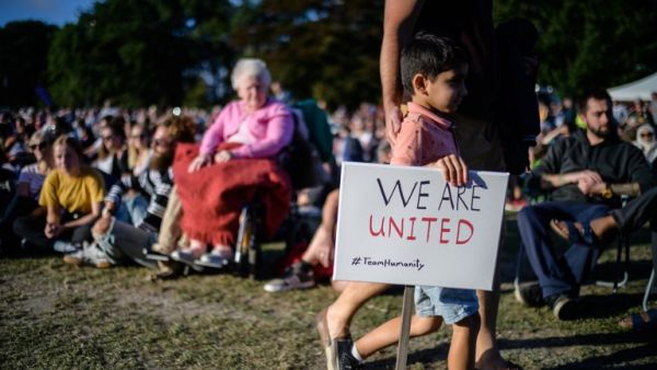 A young boy carries a placard that reads "We Are United" during a vigil held in memory of the twin mosque massacre victims in Christchurch (AFP)