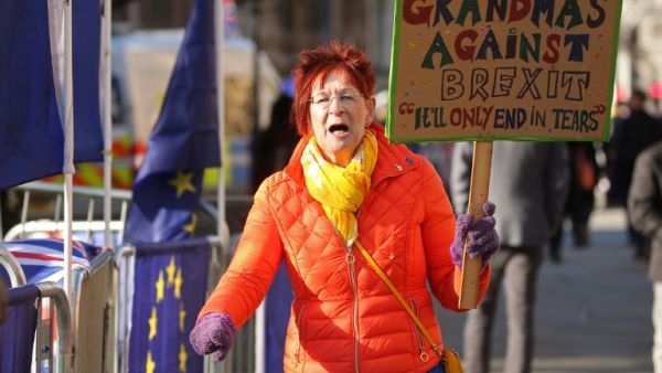 An anti-Brexit campaigner holds up a "Grandmas against Brexit" placard as she protests outside the Houses of Parliament in London (AFP)