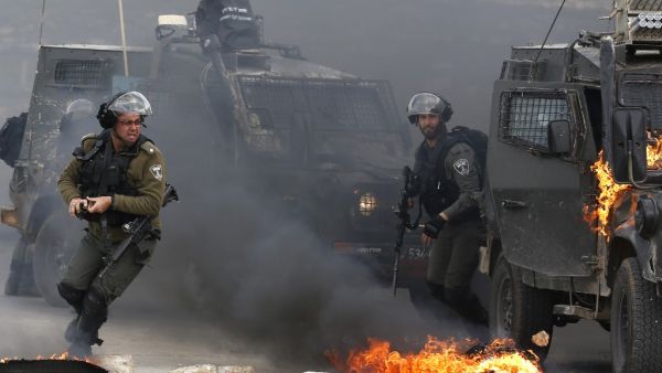 Israeli border guards move away from a burning military vehicle during clashes with Palestinian demonstrators who took to the streets on the outskirts of Ramallah in West Bank. (AFP/ File)