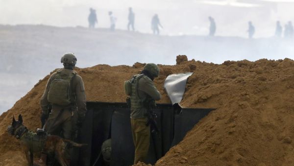 Israeli soldiers gather at a position over an earth barrier along the border with the Gaza Strip (AFP)