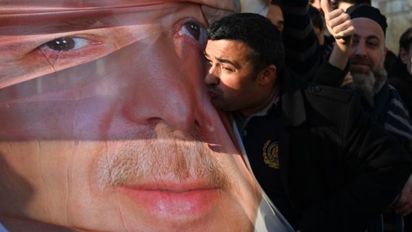 Supporters of ruling Justice and Development Party (AKP) hold a banner picturing Turkish President Recep Tayyip Erdogan while one of them kiss it as they shout slogans during a gathering outside the party's headquarters a day after the local elections (AFP)