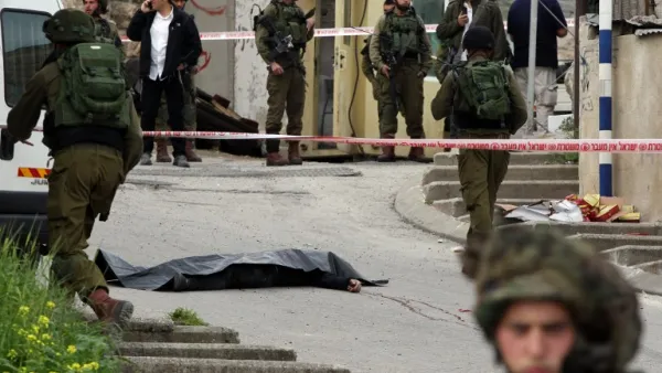 Israeli soldiers surround the body of one of the two Palestinians who were killed after wounding an Israeli soldier in a knife attack before being shot dead by troops in Hebron on March 24, 2016. (AFP/Hazem Bader)