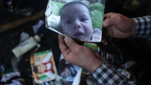 A man shows a picture of 18-month-old Palestinian toddler Ali Saad Dawabsha who died when his family house was set on fire by alleged Jewish extremists in the West Bank village of Duma on July 31, 2015. (AFP/Jaafar Ashtiyeh)