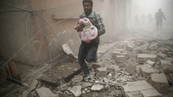 Man carries a baby in bomb-shelled Douma, Syria, AFP/File