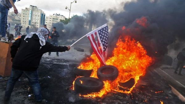 A Palestinian protester sets alight an America flag during clashes with Israeli troops at a protest against President Trump's decision to recognize Jerusalem as the capital of Israel. (ABBAS MOMANI / AFP)