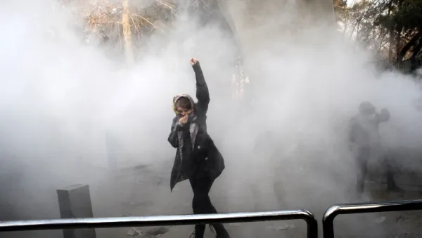 An Iranian woman raises her fist amid the smoke of tear gas at the University of Tehran during a protest driven by anger over economic problems in the capital Tehran on Dec. 30, 2017 (STR / AFP)