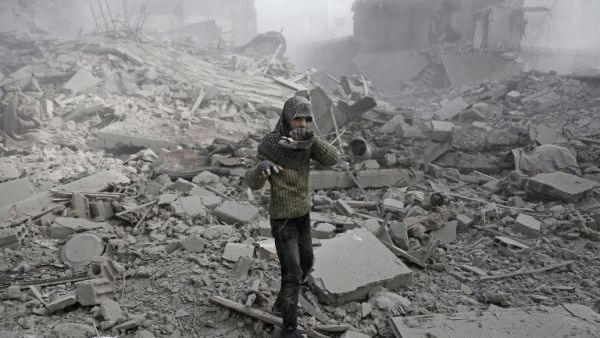 A Syrian girl appears from the rubble holding her shoe following an air strike on Hamouria, in the besieged rebel-held Eastern Ghouta area near Damascus, on Jan. 9, 2018 (ABDULMONAM EASSA / AFP)
