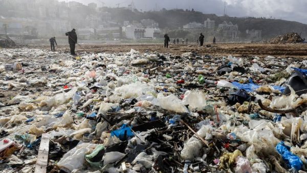 Workers clean the beach of the coastal town of Zouk Mosbeh, north of Beirut, on Jan. 23, 2018 as garbage washed and piled along the shore after stormy weather (JOSEPH EID / AFP)
