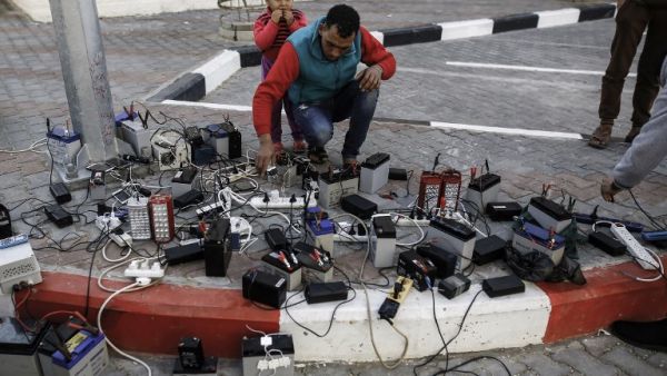 Palestinian charge their mobile phones from batteries, a free service offered in a neighborhood suffering from power cuts, in Gaza City on Feb. 1, 2018 (MOHAMMED ABED / AFP)