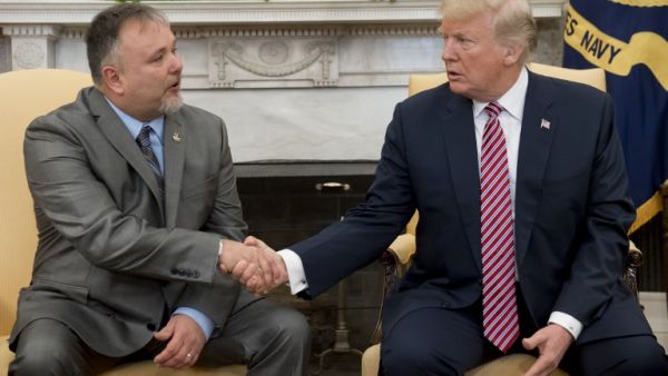 U.S. President Donald Trump shakes hands with Donald Bouvet (L), the father of a Trump presidential campaign volunteer who received a check for $10,000 from Trump with the money being used to treat Bouvet's bladder cancer, during a meeting in the Oval Office of the White House in Washington, DC, Feb. 9, 2018. 
(SAUL LOEB / AFP)