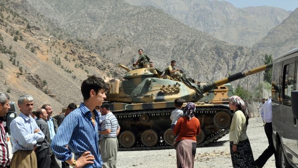 People stand near armored vehicles of Turkish military stationed in front of Gecimli military outpost where Kurdish rebels attacked and killed 6 soldiers and 2 village guard on 5 August in Hakkari. (AFP/File)