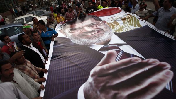 Ousted President Mohamed Morsi supporters and Muslim Brotherhood members hold a giant portrait of him as they demonstrate against his toppling at Raba al-Adwyia mosque on July 7, 2013 in Cairo.
(AFP/File)