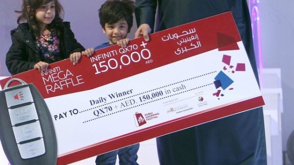 Three-year-old Talal Al Hammar accepts his reward for winning the Dubai Shopping Festival raffle. (Twitter) 