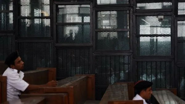Egyptian Muslim Brotherhood defendants, including leader Mohamed Badie, stand behind bars during a trial in Cairo. (AFP/ File Photo)