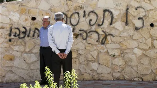 Arab Israeli men stand next to graffiti reading in Hebrew "Arabs Out" on the wall of a mosque in the northern Israeli city of Umm al-Faham. AFP Photo

