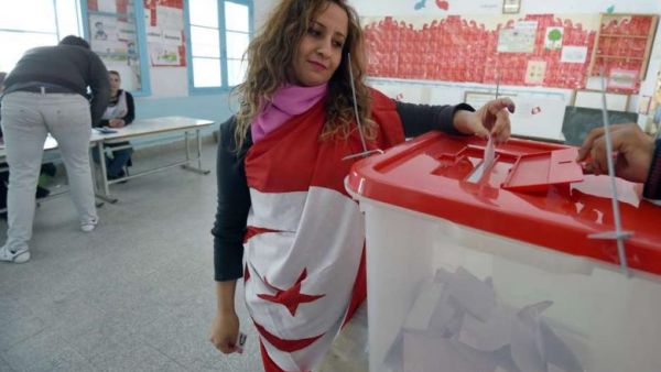 A Tunisian woman wearing the national flag casts her vote (AFP/File Photo)