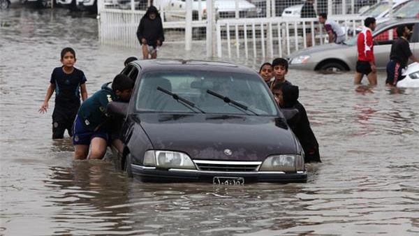 Iraqi children push a car through Baghdad during a similar flood in November 2013 (AFP / Ahmad Al-Rubaye)