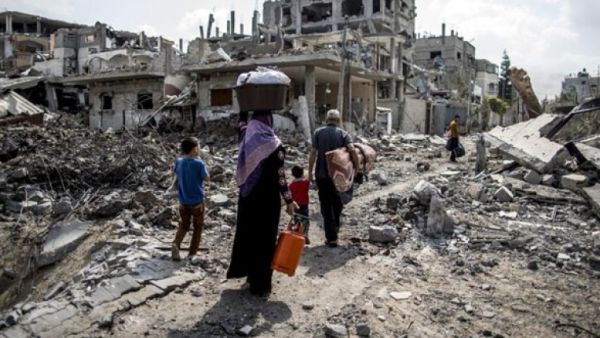 A displaced Palestinian family walks through a northern Beit Hanun neighborhood in the Gaza Strip. (AFP/File)
