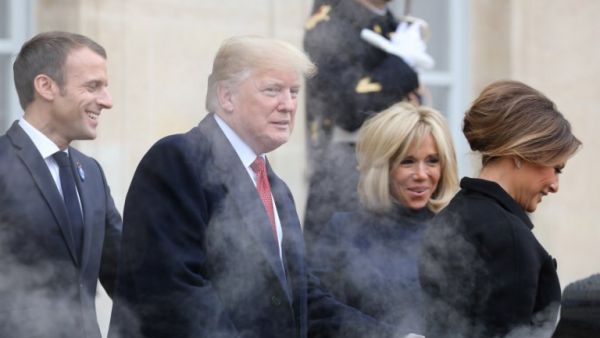 Smoke billows from the exhaust of the US president's official state car, also known as 'The Beast', as French President Emmanuel Macron (L) and his wife Brigitte Macron (R) bid farewell to U.S. President Donald Trump and First Lady Melania Trump at the Elysee Palace in Paris on November 10, 2018 Ludovic MARIN / AFP