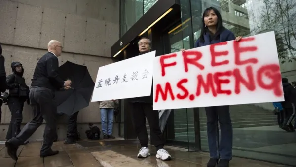Robert Long (L) and Ada Yu hold signs in favor of Huawei Technologies Chief Financial Officer Meng Wanzhou outside her bail hearing at British Columbia Superior Courts following her December 1 arrest in Canada for extradition to the US, in Vancouver, British Columbia on December 11, 2018. 
Jason Redmond / AFP