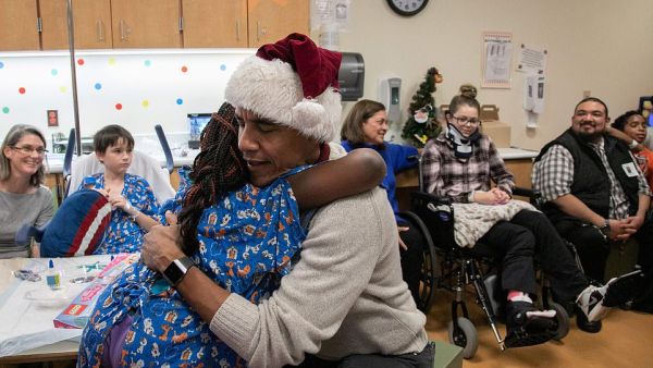 Obama hugs a girl after presenting a Christmas gift to her in the hospital in DC (AFP)
