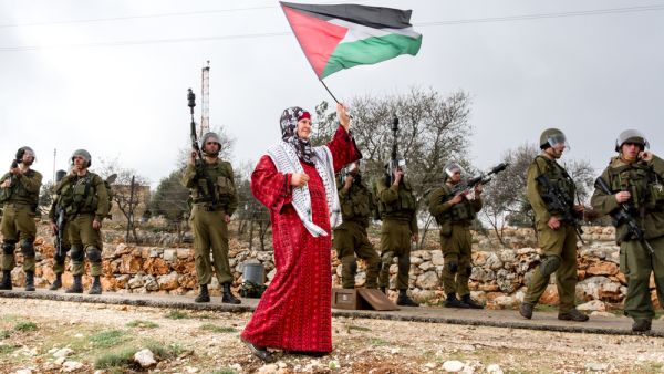 Palestinian woman walks with Palestinian flag (Shutterstock)	