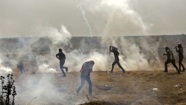 Palestinians take cover from tear gas smoke fired by Israeli force (AFP/File Photo)	