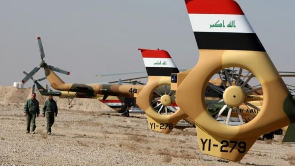 Members of Iraq's air force walk past a line of helicopters. (AFP/File)