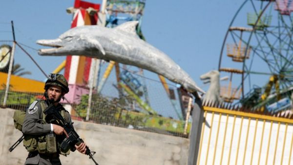 An Israeli soldier stands guard in front of an amusement park during a military operation carried out to arrest Palestinian militants in the West Bank city of Jenin on Sunday. (AFP PHOTO/SAIF DAHLAH)