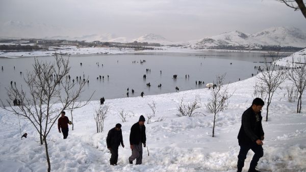 Afghan men climb up a snow covered hillside as youths play on the frozen surface of Qargha Lake on the outskirts of Kabul on February 10, 2017. (AFP/Wakil Kohsar)