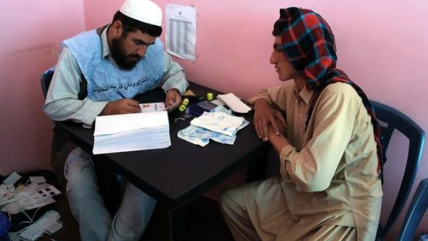 An Afghan man waits to receive his identification card to vote in upcoming elections. [AFP]