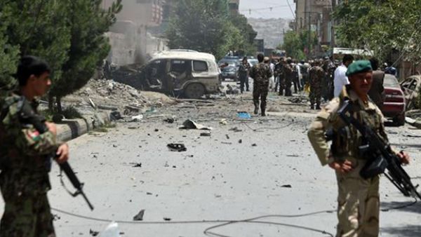 Security personnel and residents walk at the site of a car bomb blast that targeted the CARE International compound at Share Naw in Kabul. (AFP/Wakil Kohsar)