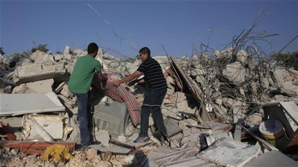 Members of a Palestinian family collect their belongings near the rubble of their house after it was demolished by Israeli forces, in Kafr Kanna. (AFP/file) 