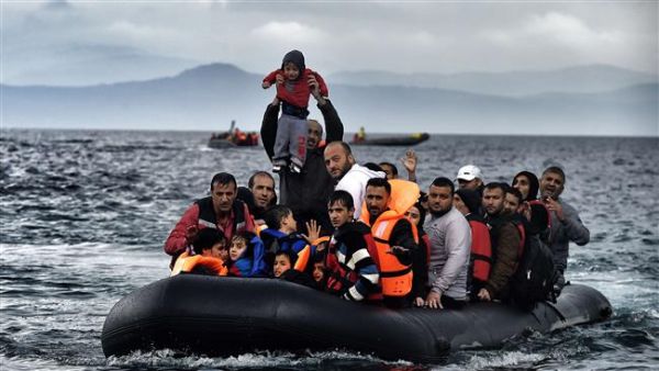 A man holds up a young boy as a boat carrying refugees arrives at the Greek island of Lesbos after crossing the Aegean Sea from Turkey. (AFP/File) 