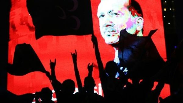 Supporters stands in front of a screen displaying a portrait of Turkish President Recep Tayyip Erdogan during a rally in Ankara on July 20, 2016. (AFP/File) 