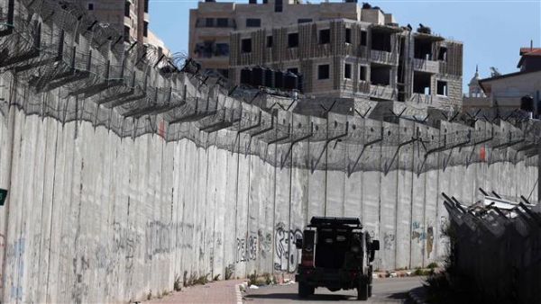 An Israeli police car patrols along a section of Israel’s Apartheid Wall that separates the West Bank city of al-Ram. (AFP/File)