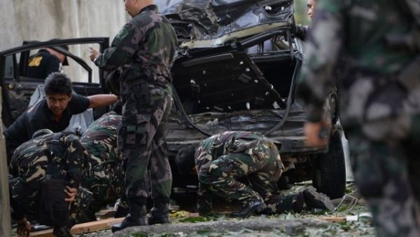 A members of Philippine police and military bomb squads look for evidence next to a destroyed car after a suspected car bomb explosion amidst heavy firefight between government troops and rebels. (AFP)