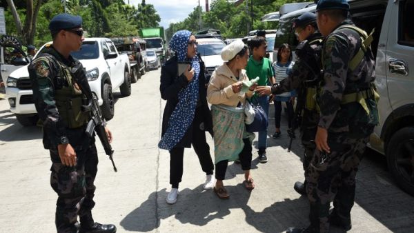 Philippine policemen check evacuees from Marawi aboard a van at a checkpoint by the entrance of Iligan City, in southern island of Mindanao on May 24, 2017. (AFP/Ted Aljibe)