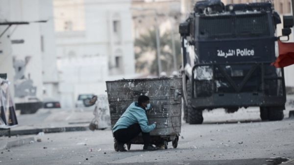 This file photo taken on January 2, 2015 shows a Bahraini protester taking cover behind a garbage container during clashes with riot police following a demonstration. (AFP/Mohamed al-Sheikh)