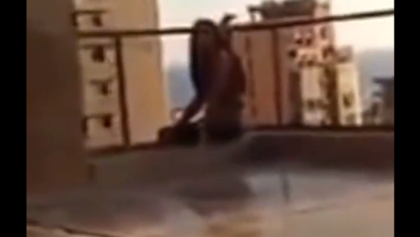 The terrifying moments before a woman throws herself off of her building. (screen grab from YouTube)