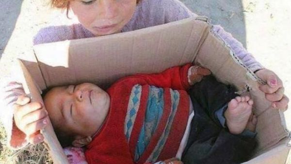A little Syria refugee holds her baby brother who froze to death. (Arabsaga)