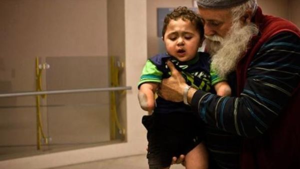 Little Mohammed has lost his arm, legs and sadly, the care of his parents. Thankfully, he has a grandfather looking after him. (AP)
