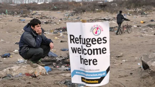 A migrant stands next to a banner in the port city of Calais, northern France, during a demonstration to support the migrants and refugees who live in the 'jungle'. (AFP/Francois Lo Presti)