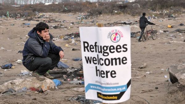A migrant stands next to a banner in the port city of Calais, northern France, during a demonstration to support the migrants and refugees who live in the 'jungle'. (AFP/Francois Lo Presti)